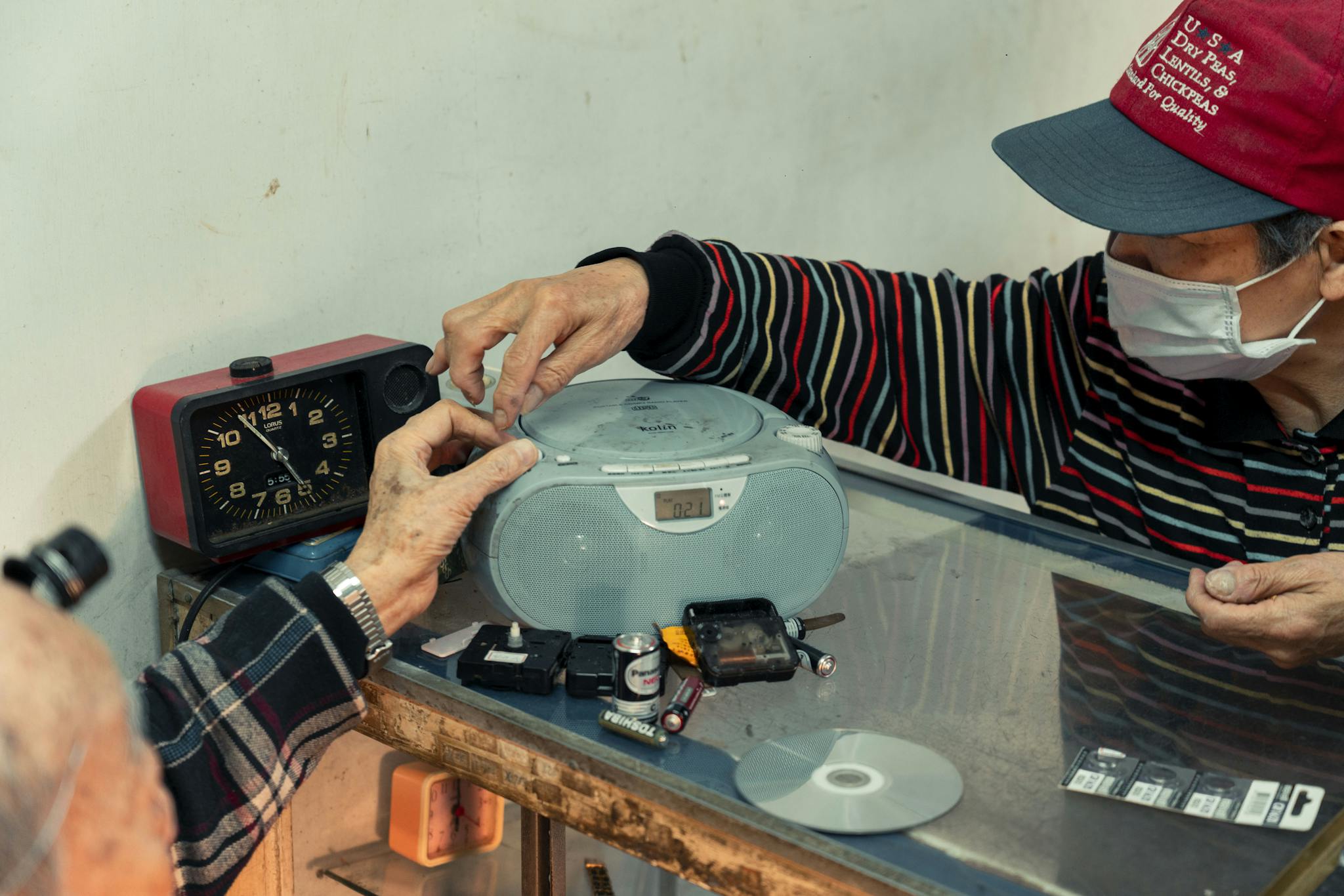 Elderly man repairing a personal stereo in a workshop, showcasing self-employment skills.